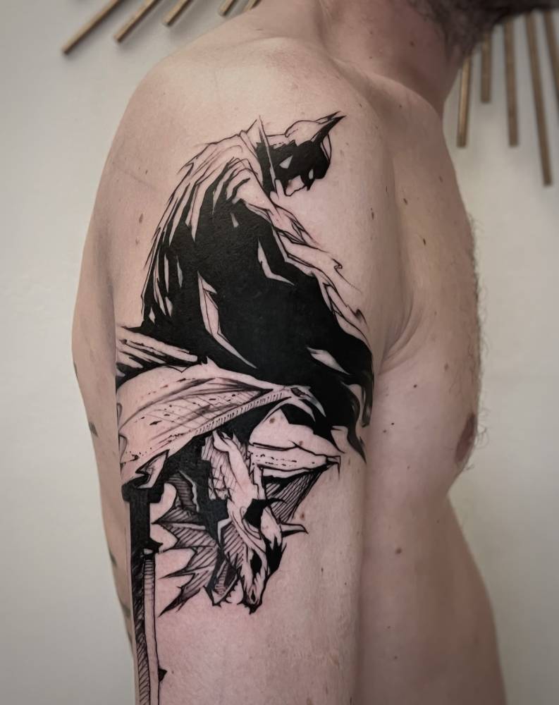Batman tattoo in blackwork style located on the upper arm.