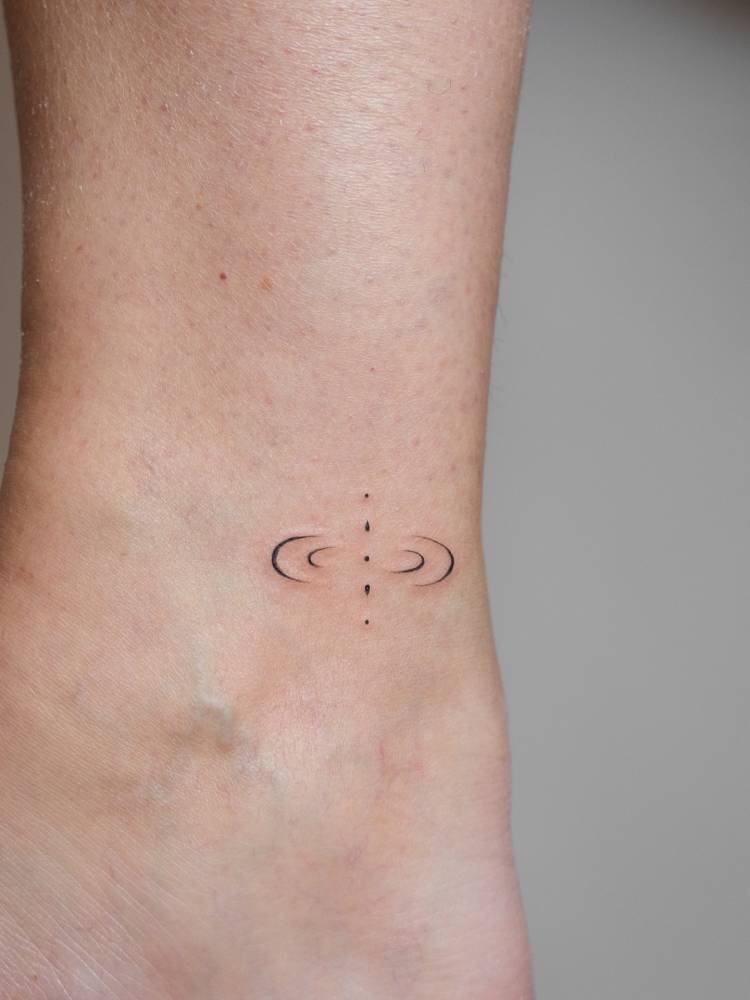 Mindfulness symbol tattoo located on the ankle, minimalistic style.