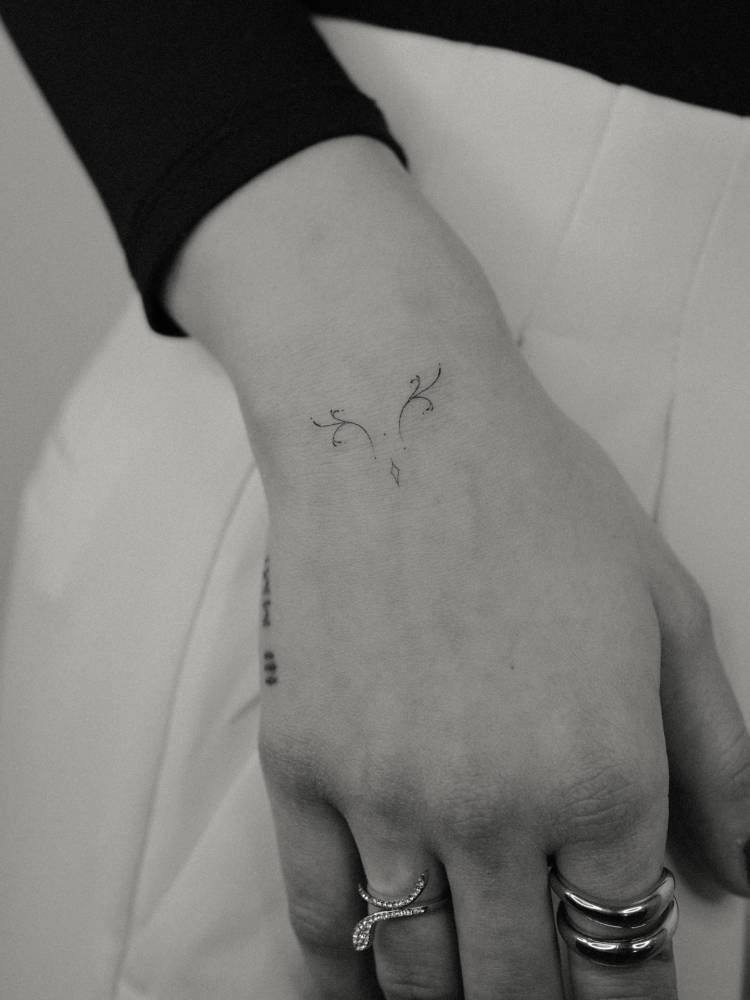 Tiny ornamental tattoo in fine line style placed on the wrist.