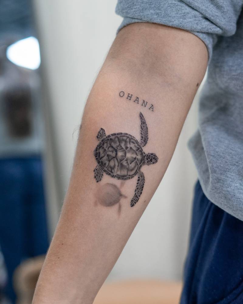 Turtle and word "ohana" tattooed on the inner forearm.