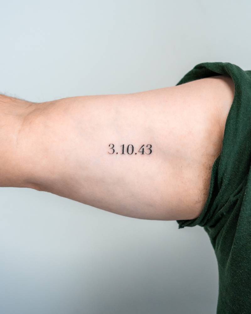 Date tattoo in serif font located on the inner arm.