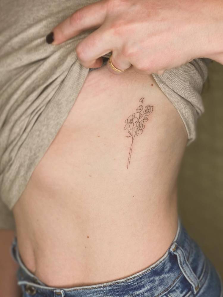 Flower bouquet tattoo in fine line style placed on the rib.