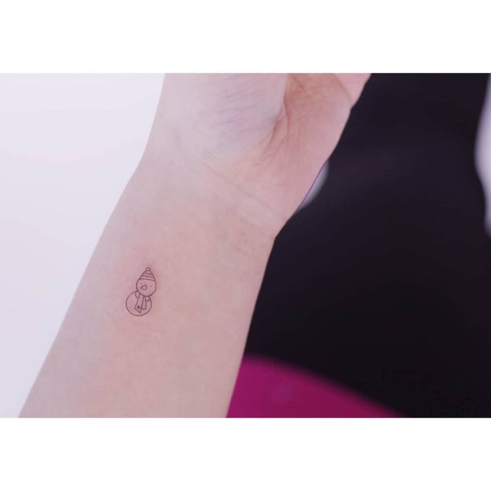 Tiny minimalistic snowman tattoo placed on the wrist.