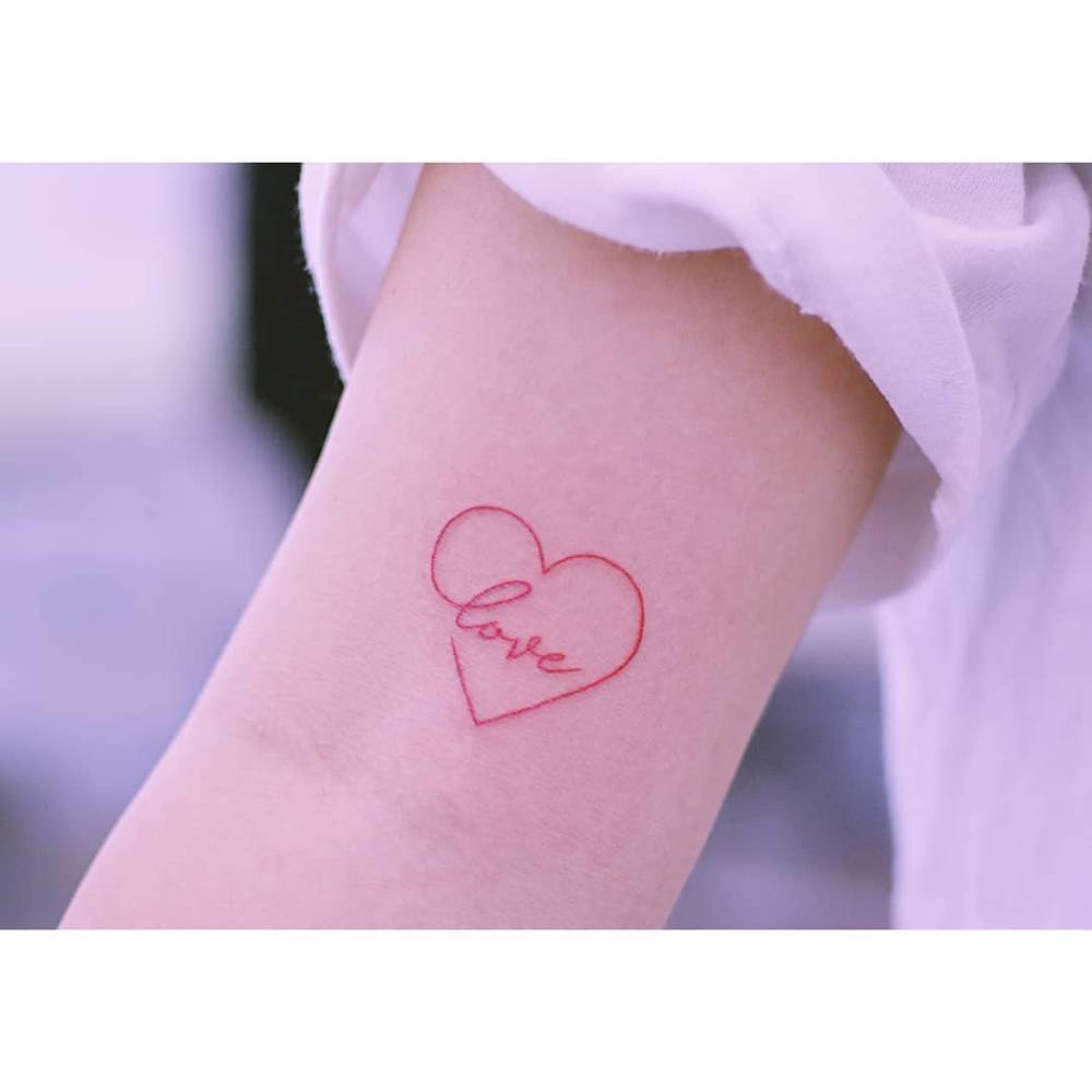 Heart and banner with the word "love" tattooed on the bicep.