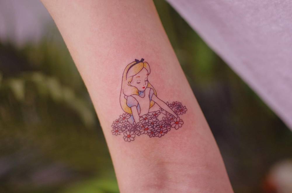 Disney's Alice tattoo located on the bicep, cartoon style.