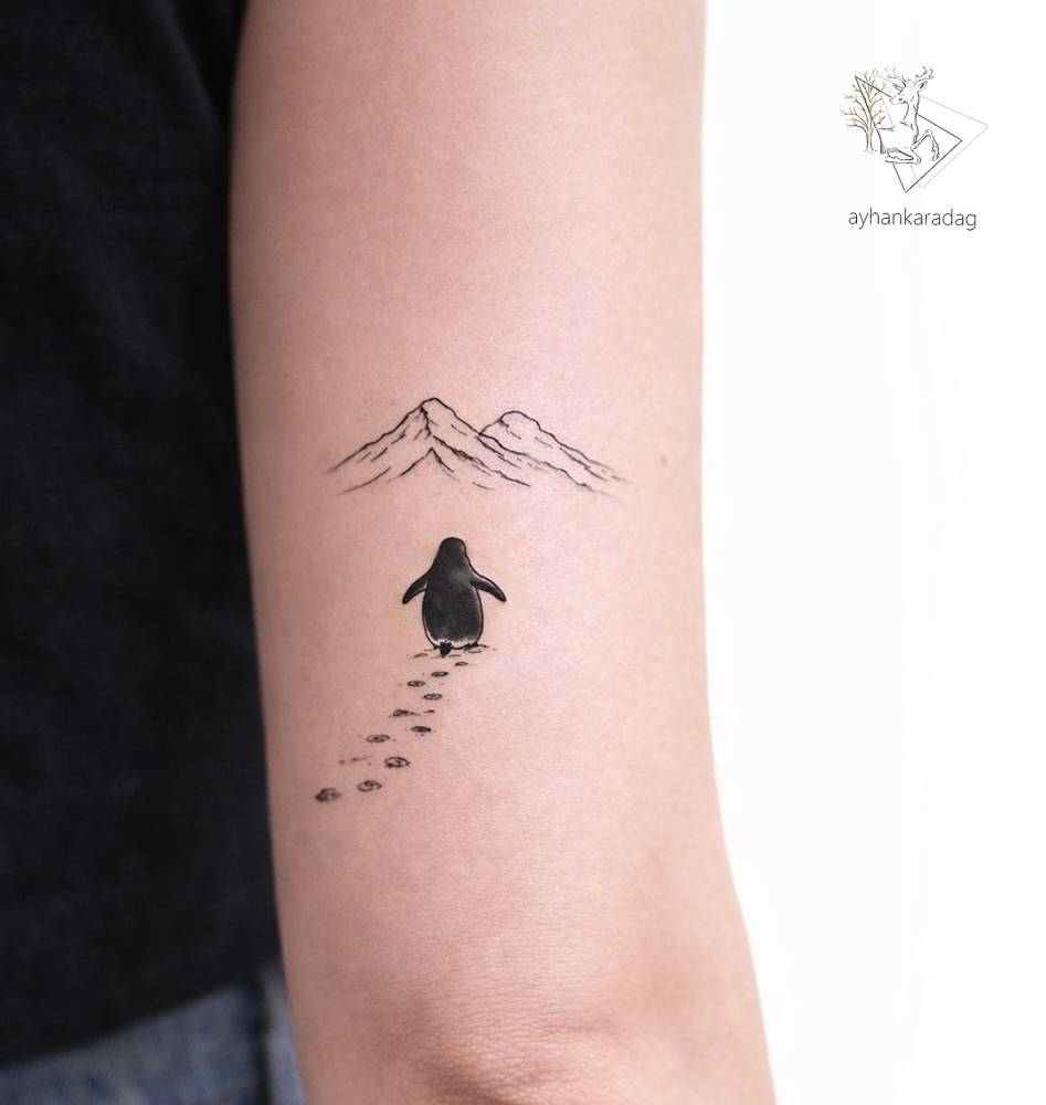 Little penguin tattoo located on the tricep, illustrative style.