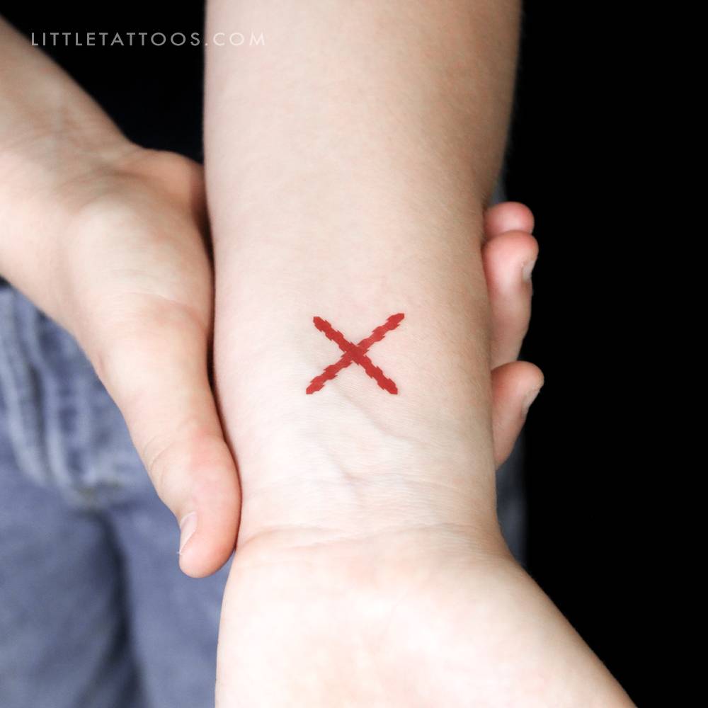 Small Cross Of Burgundy temporary tattoo located on the wrist.