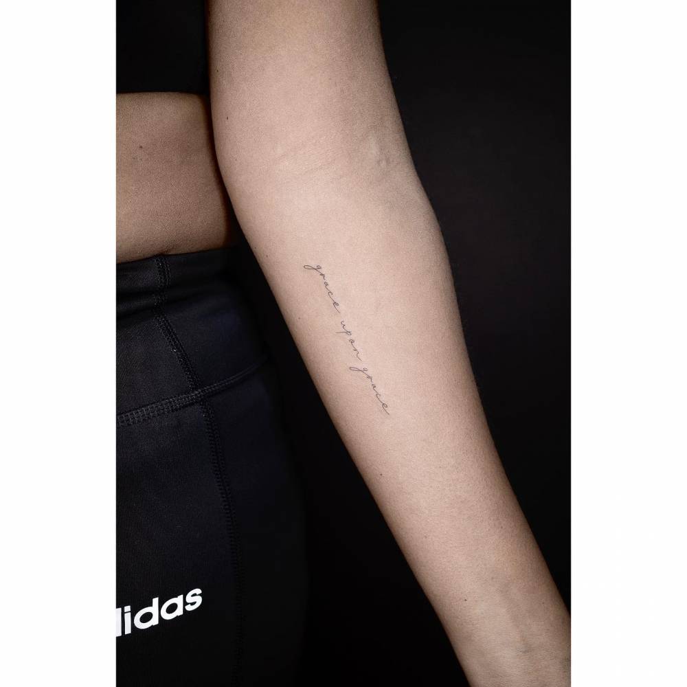 Tattoo that says "grace upon grace" located on the inner forearm.