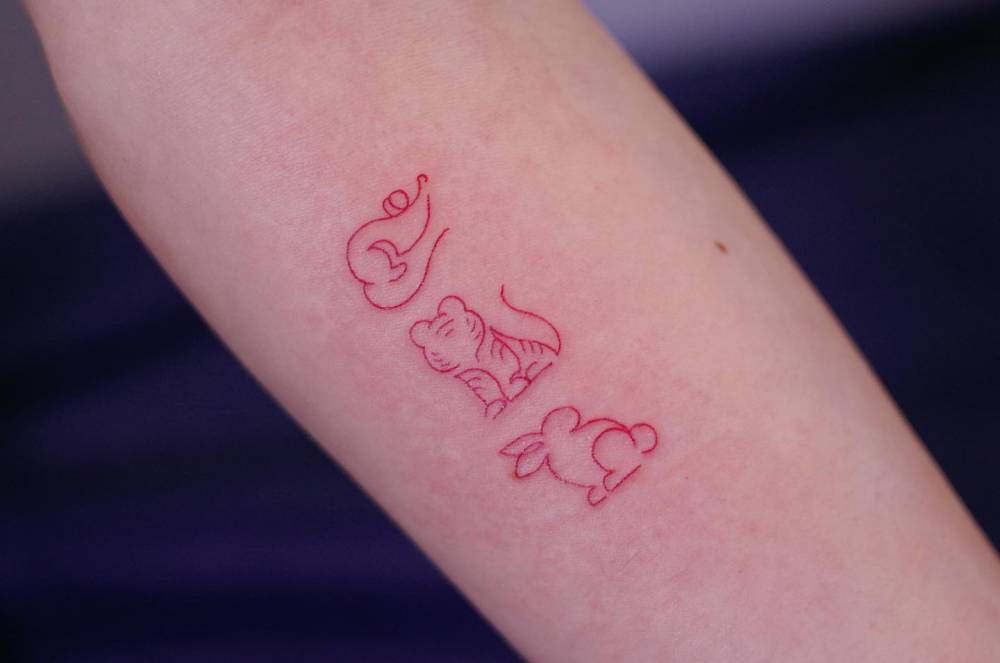 Mouse, tiger and rabbit tattoo in red ink located on the inner forearm.