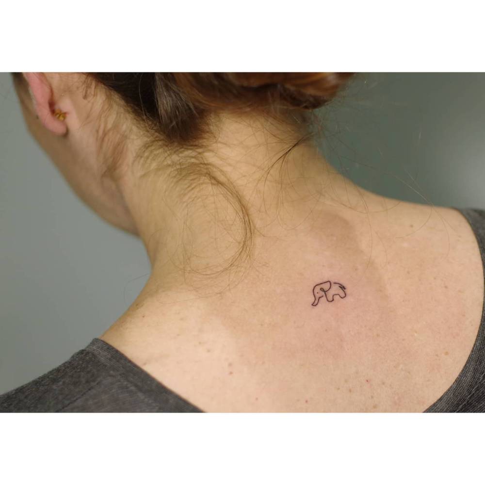Tiny minimalistic elephant tattoo placed on the upper back.