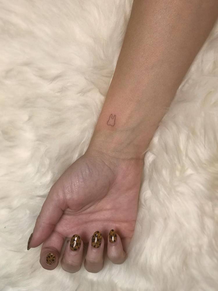 Tiny minimalistic tooth tattooed on the wrist.