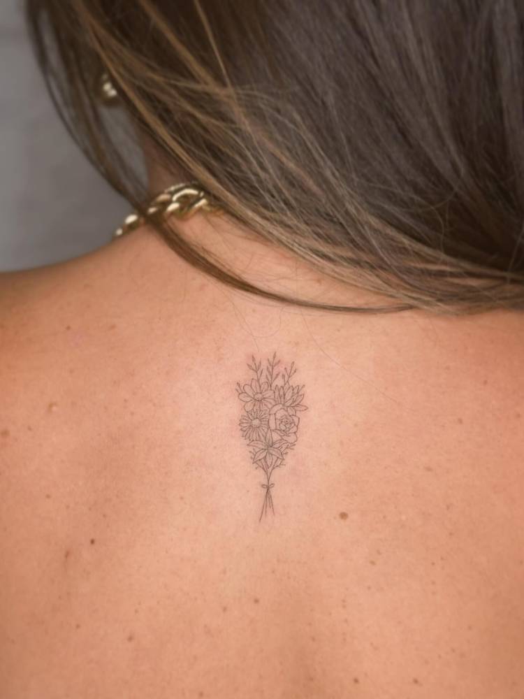 Flower bouquet tattoo in fine line style located on the upper back.