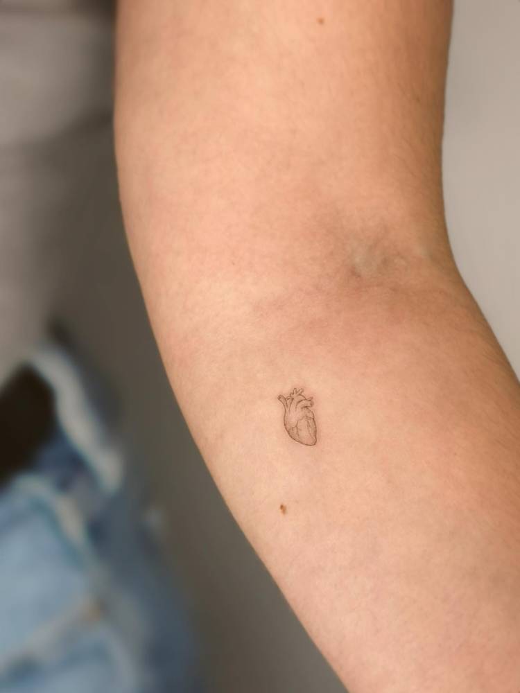 Micro anatomical heart tattoo in minimalistic style.