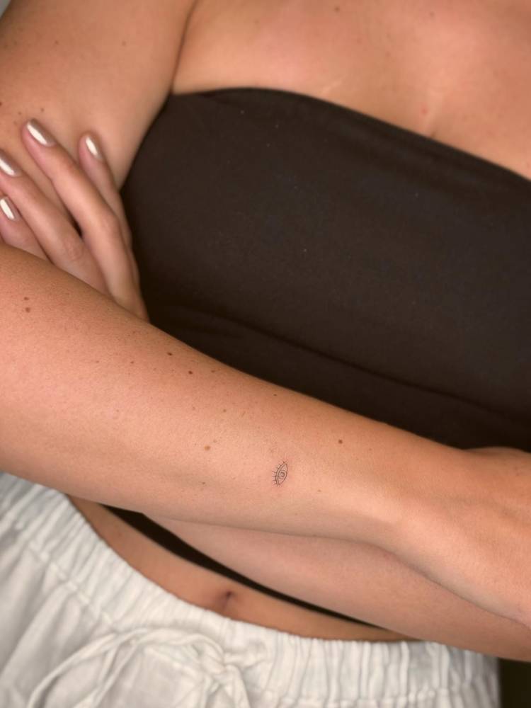 Minimalistic evil eye tattoo located on the wrist.
