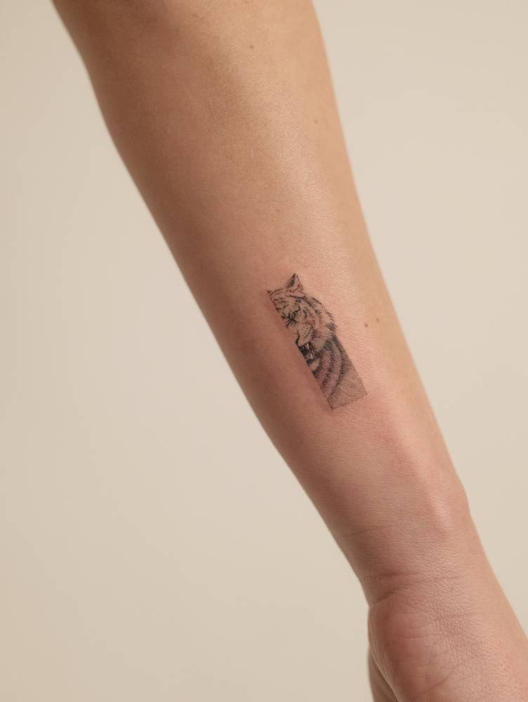 Micro-realistic style tiger portrait tattoo located on the wrist.