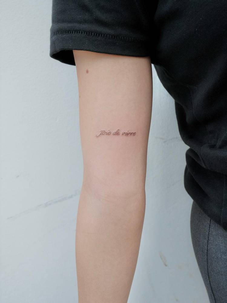 "Joie de vivre" lettering tattoo located on the inner arm.