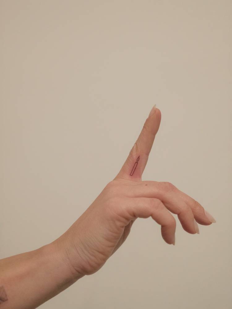 Little candle tattoo done on the finger, minimalistic style