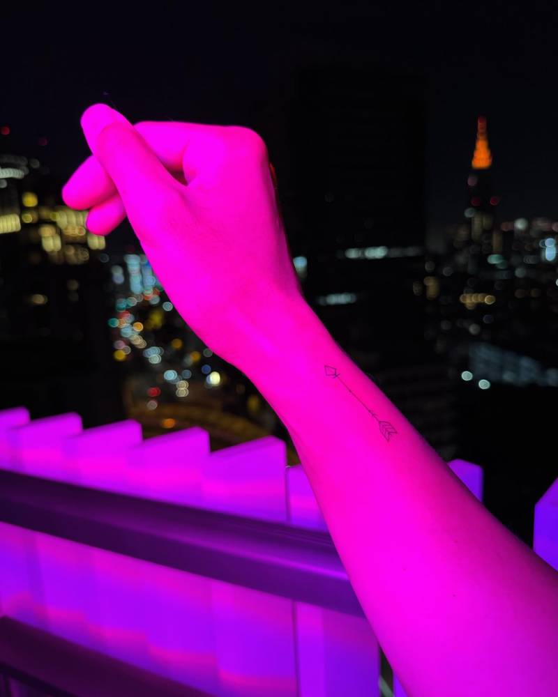 Arrow tattoo located on the wrist, done in fine line style.