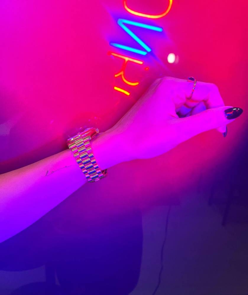 Handwritten font word "love" tattooed on the wrist.