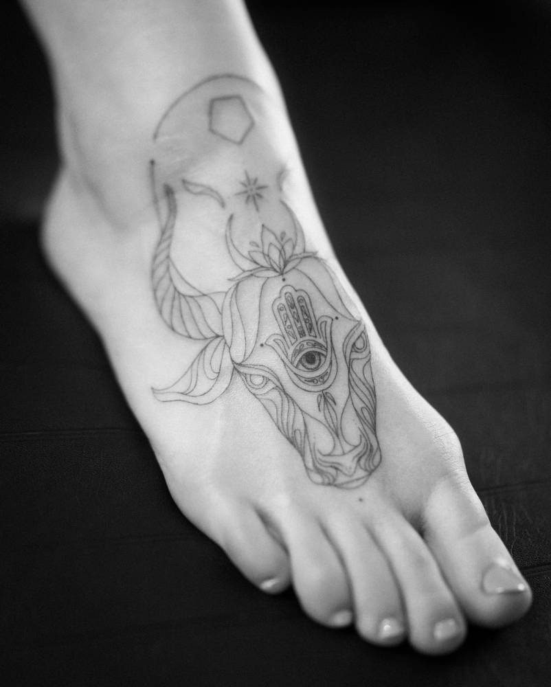 Ornamental bull head tattoo located on the foot.