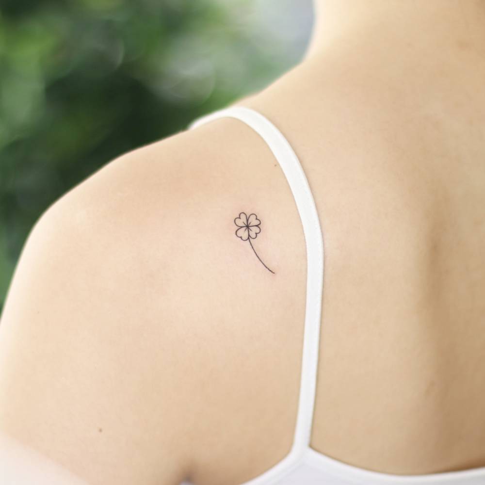 Four leaf clover tattoo placed on the shoulder blade, minimalistic style.