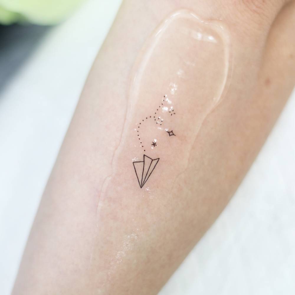 Little paper plane tattoo in fine line style done on the forearm.