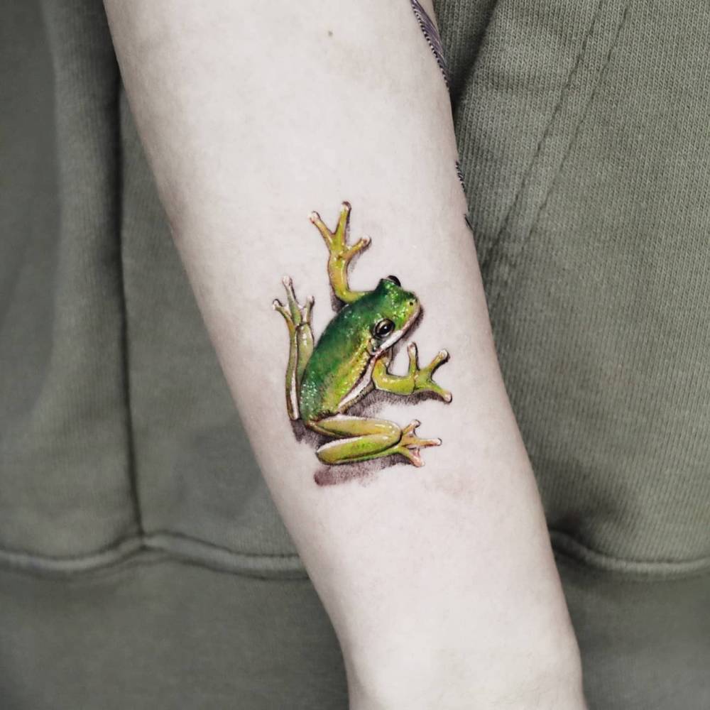Micro-realistic style frog tattoo located on the forearm.