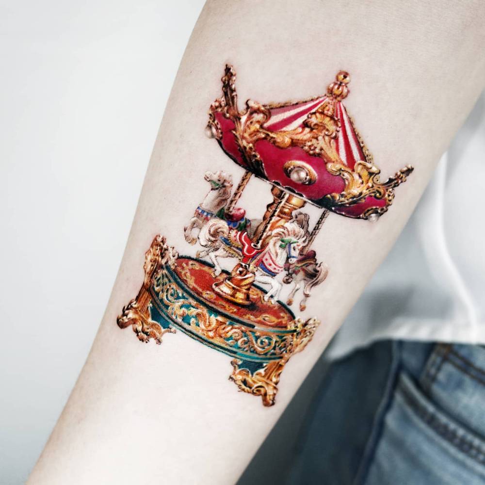 Carousel tattoo placed on the inner forearm, done in micro-realism.