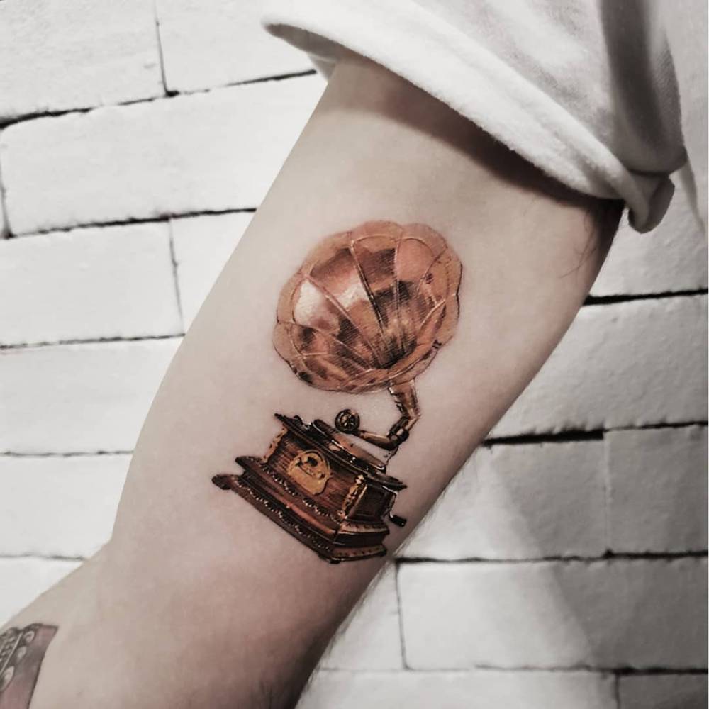Micro-realistic style gramophone tattoo located on the inner arm.