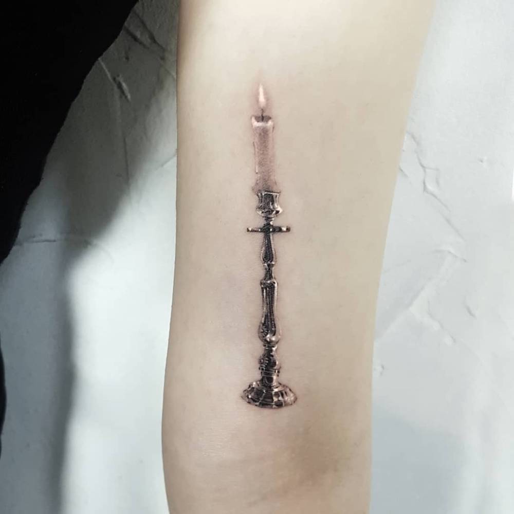 Candle tattoo located on the inner arm, micro-realistic style.
