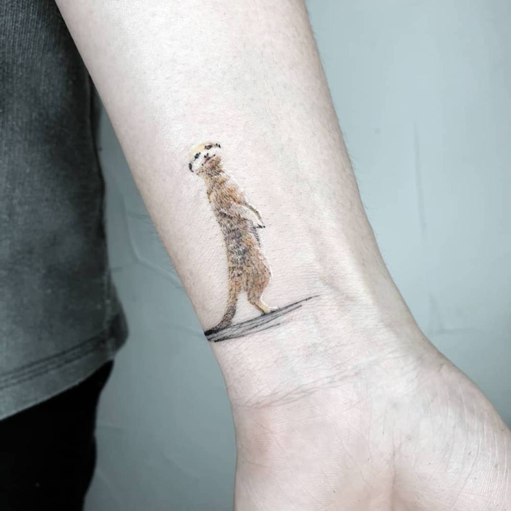 Meerkat in micro-realism tattooed on the wrist.