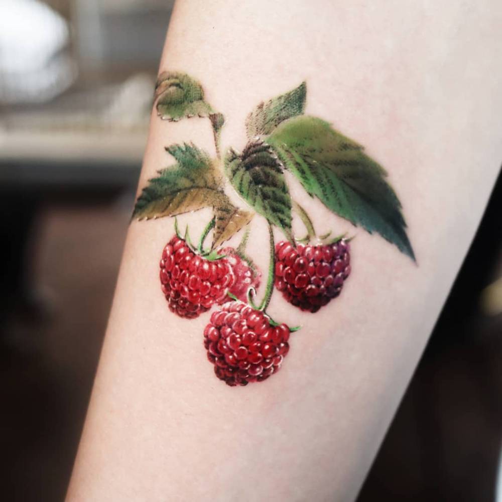 Raspberries tattoo located on the inner forearm, micro-realistic style.