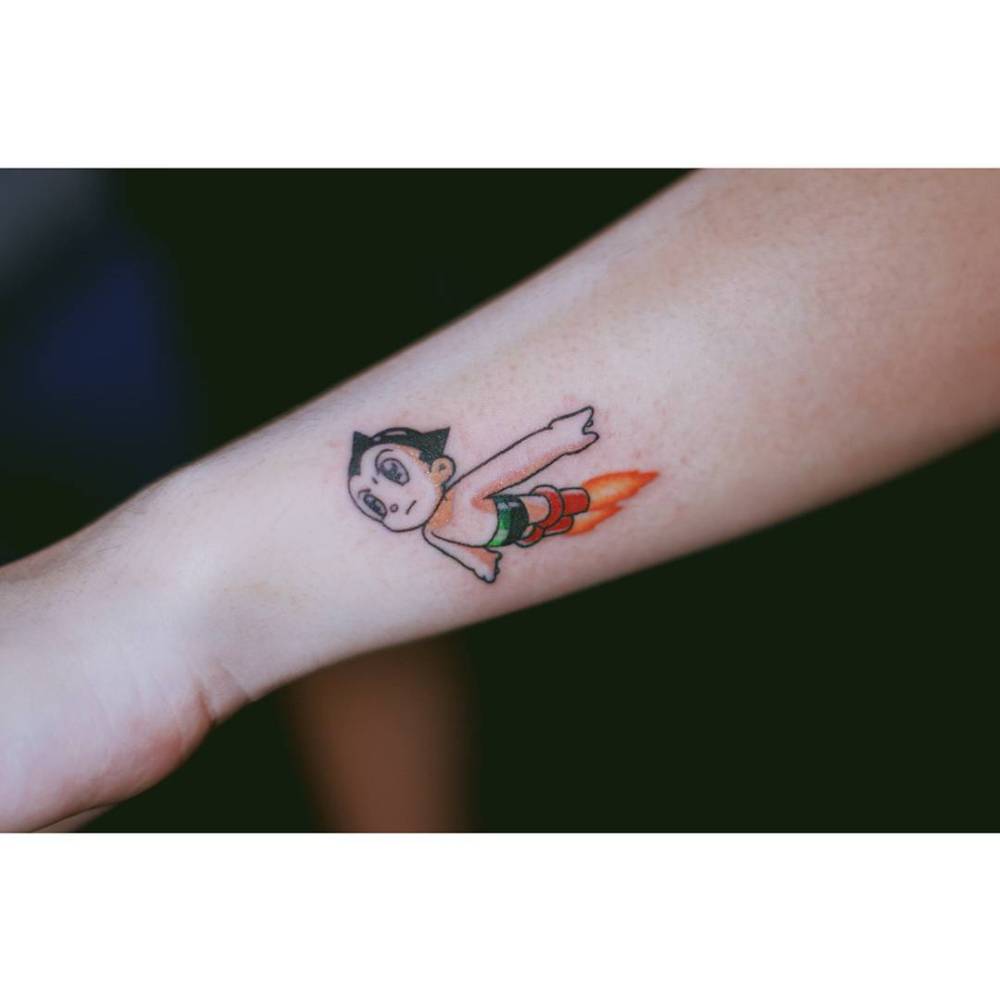 Astro Boy tattoo in cartoon style located on the wrist.