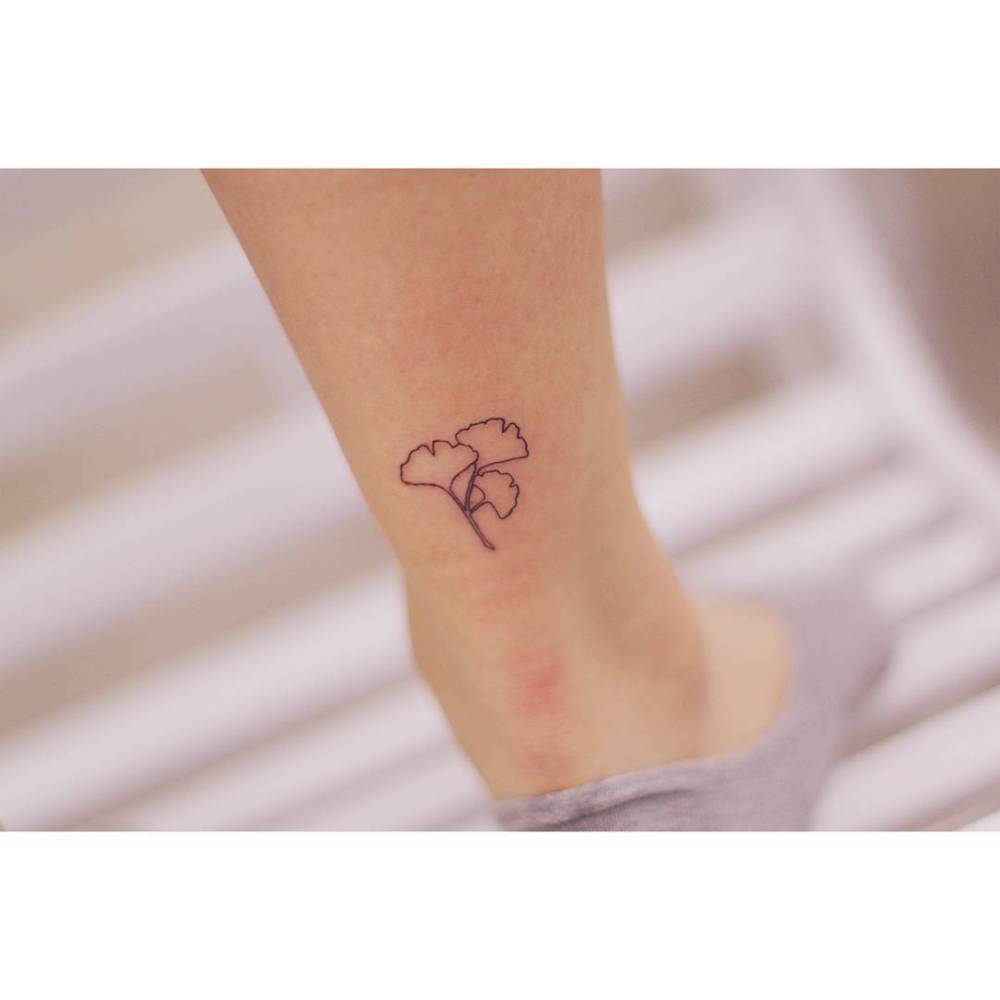 Ginkgo leaves tattoo done on the Achilles, minimalistic style.