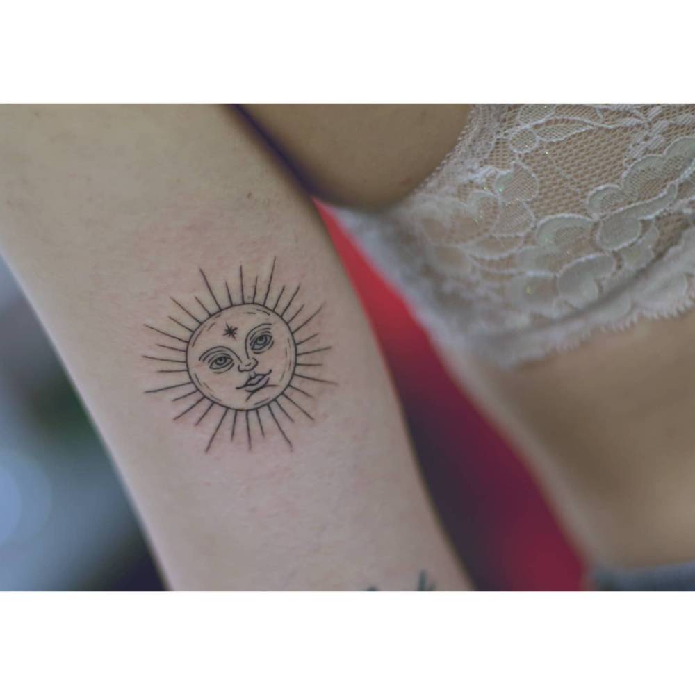 Inti sun tattoo in illustrative style located on the inner arm.