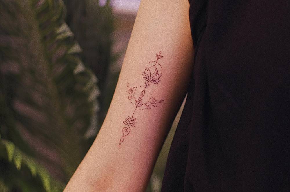 Lotus unalome tattoo inf fine line style located on the bicep.