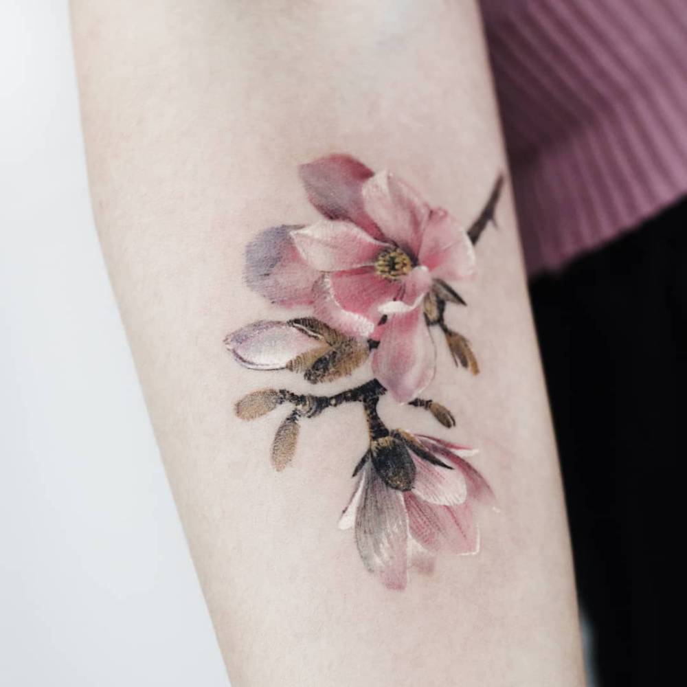 Magnolias tattoo in micro-realistic style located on the inner forearm.