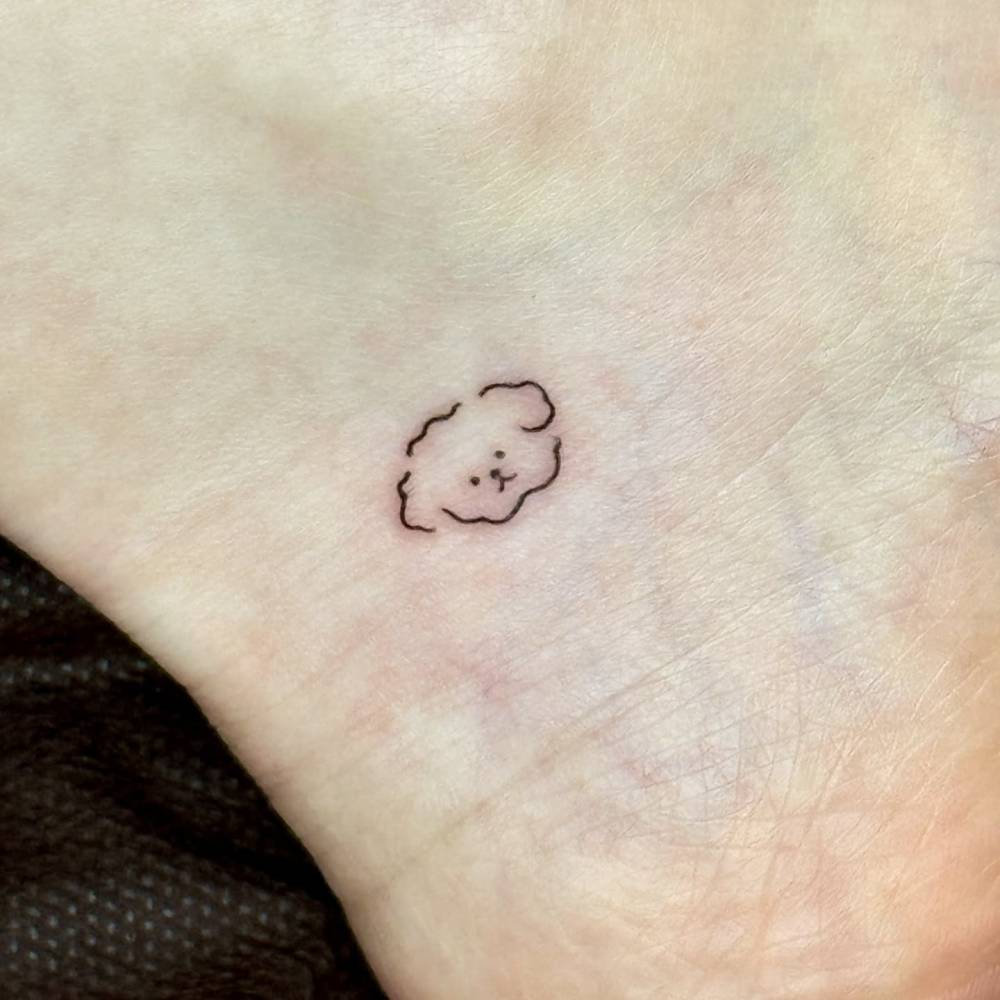 Minimalistic style tiny dog portrait tattoo placed on the ankle.