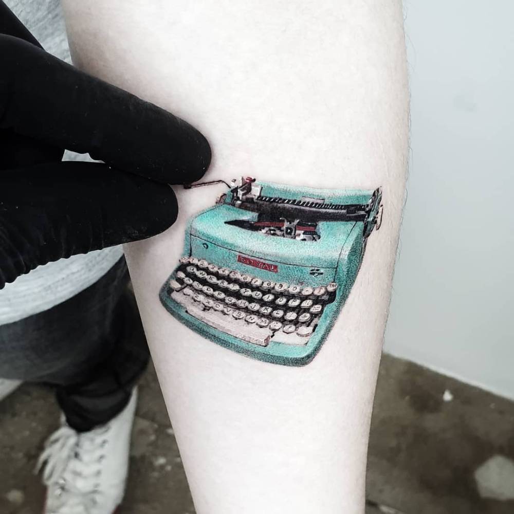 Micro-realistic style typewriter tattoo placed on the inner forearm.