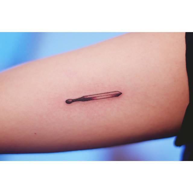 Burnt matchstick tattoo in illustrative style located on the inner arm.