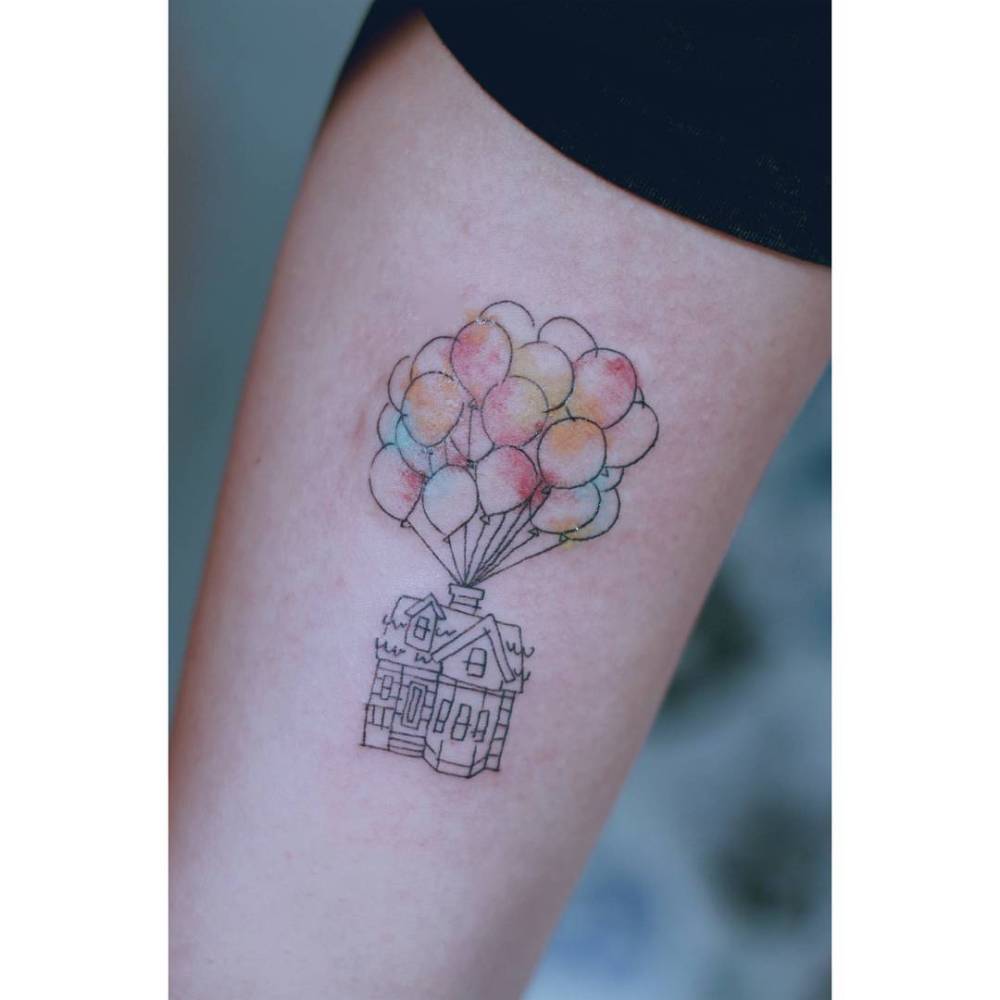 'Up' house tattooed on the inner arm, cartoon style.