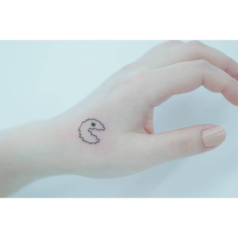 Pixelated Pac-Man tattoo in minimalistic style done on the hand.