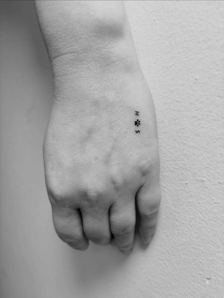 Initials and dog paw print tattoo located on the hands.