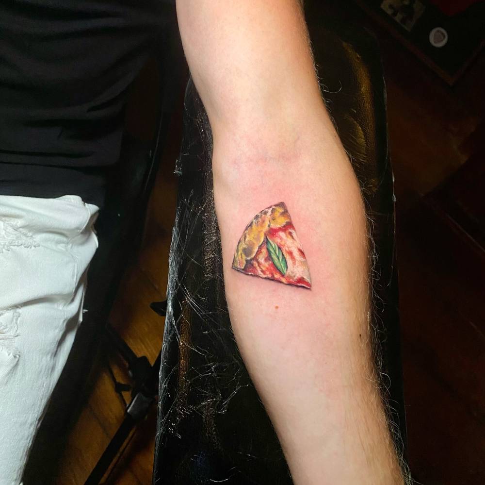Margherita pizza tattoo in micro-realistic style placed on the inner forearm.