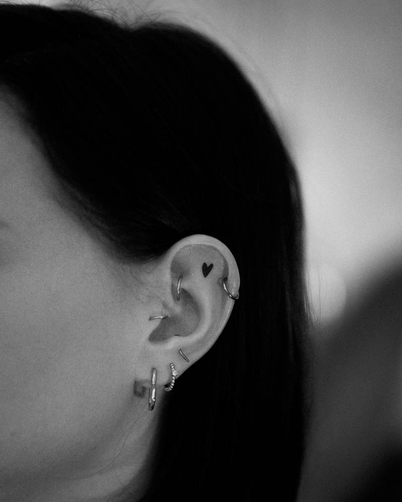 Minimalistic style star tattoo located on the ear.