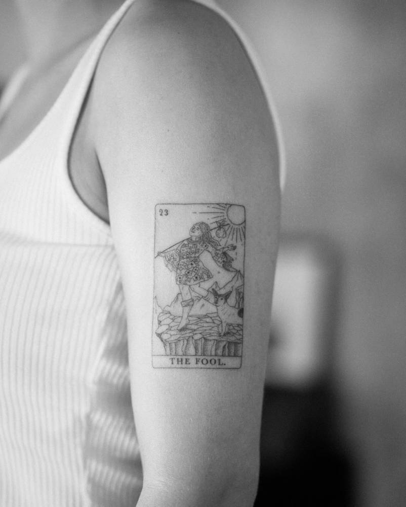 Fine line style "The Fool" tarot card located on the upper arm.