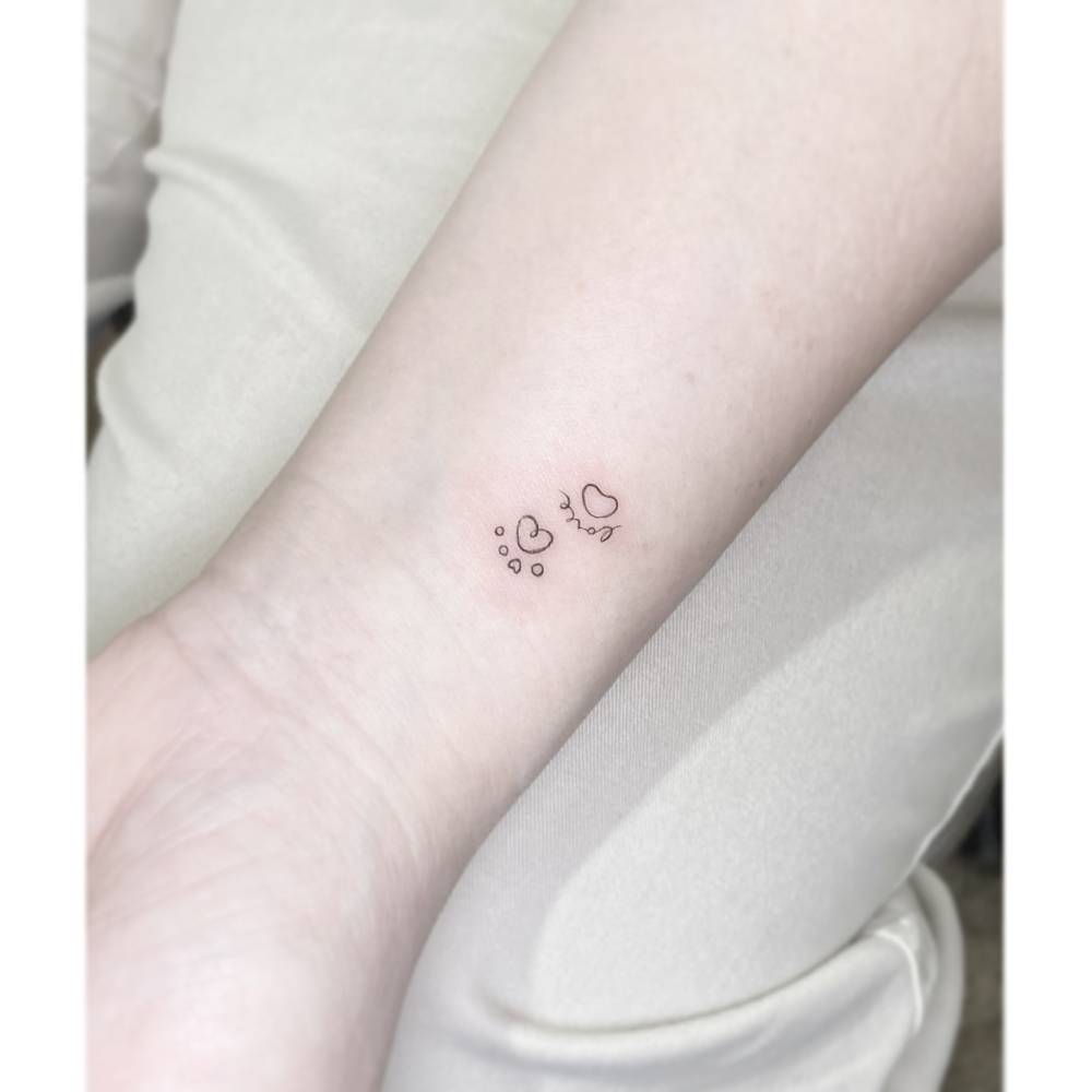 Dog paw prints with the word "love" tattooed on the wrist.