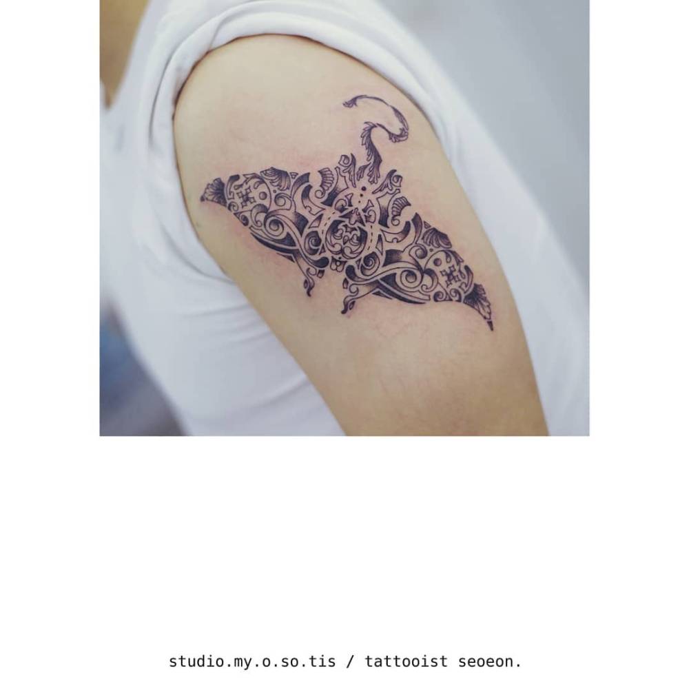 Tribal manta ray tattoo located on the upper arm.