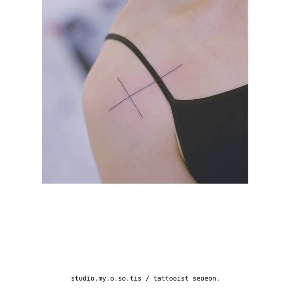 Line art style cross tattoo done on the shoulder.