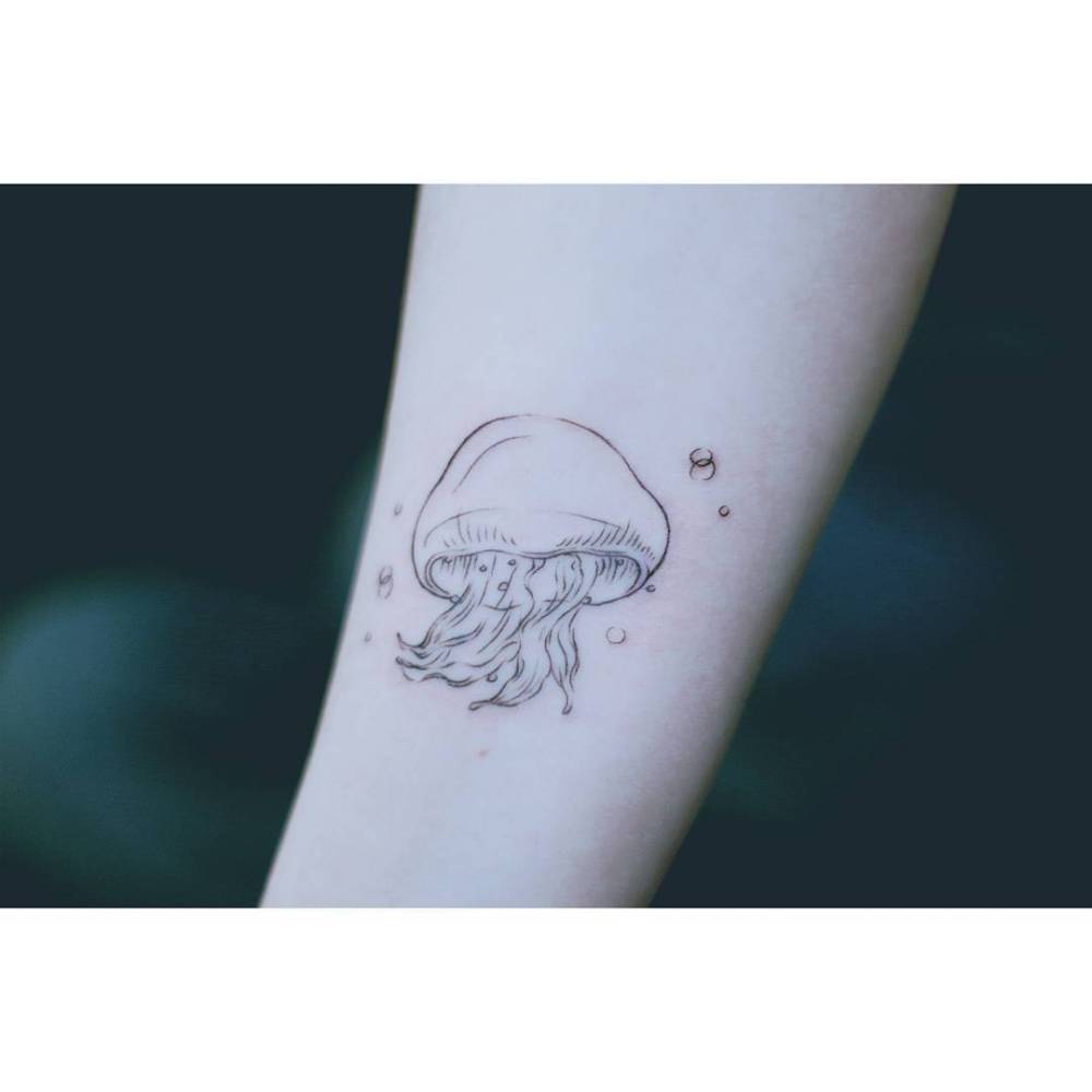 Little jellyfish tattoo located on the inner forearm, illustrative style.